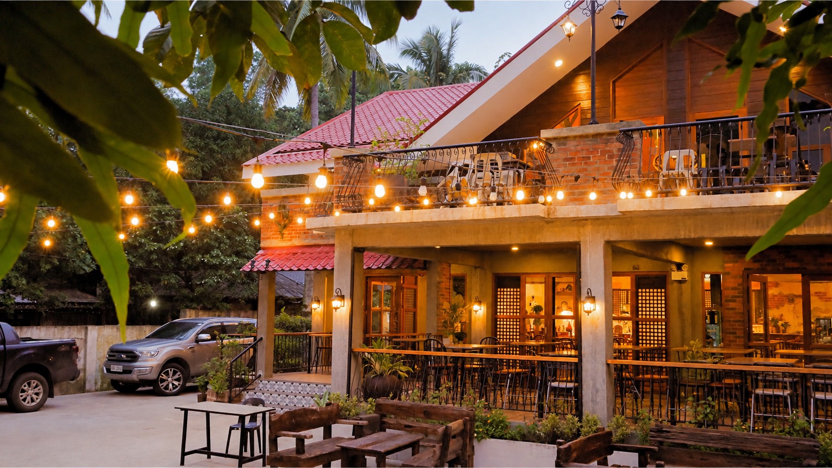 Arco Diez Cafe at dusk: the brick and timber house lit up, string lights over the garden, and the terrace tables set and waiting.